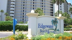 A sign for Edgewater Beach Resort with a modern building in the background.
