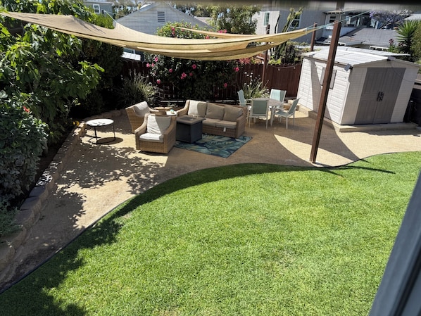A backyard with outdoor furniture, a hammock, and a shed.