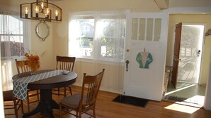 Un comedor con una mesa, sillas, una araña y una puerta con un letrero que dice 'WELCOME'.