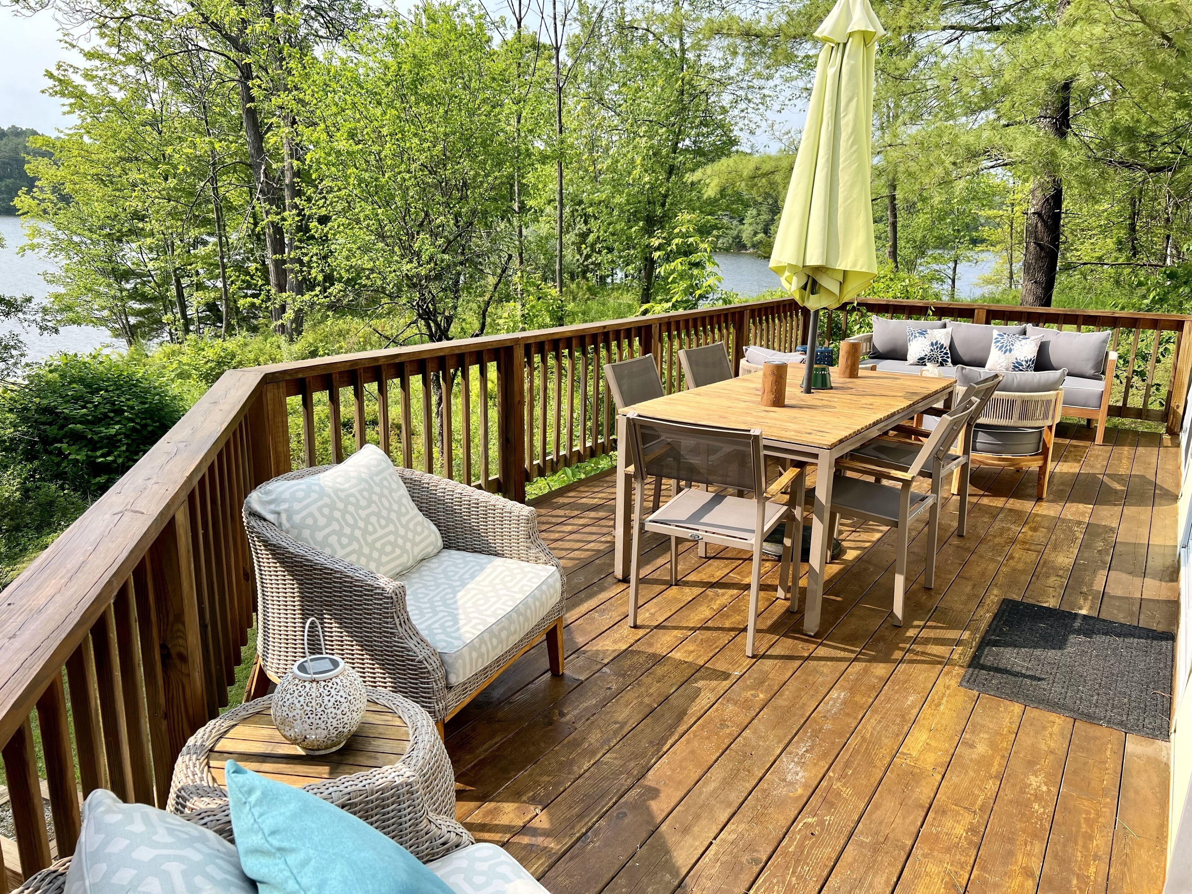 Een houten terras met tuinmeubilair, waaronder een tafel, stoelen en een bank.