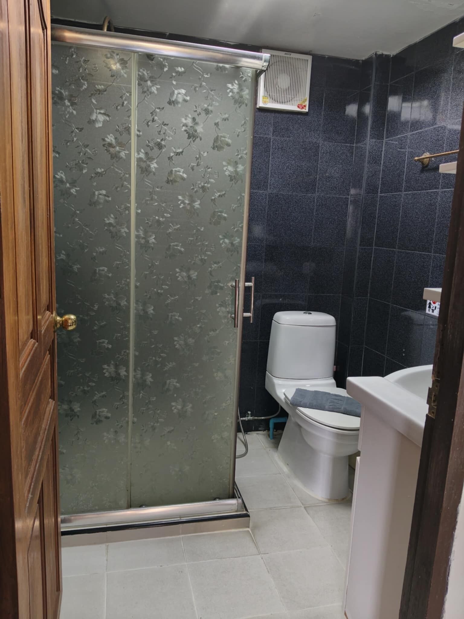 A bathroom with a glass shower door, a toilet, and a sink.