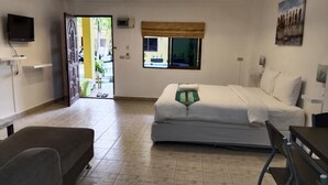 A bedroom with a bed, a desk, a chair, a TV, and a window. - Phratamnak Inn (Pattaya)
