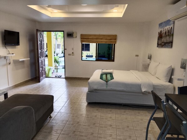 Une chambre à coucher avec un lit, un bureau, une chaise, une télévision et une fenêtre.