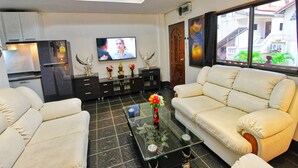 A modern living room with a sofa, a coffee table, and a TV. - Phratamnak Inn (Pattaya)