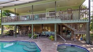 A two-story house with a covered patio, a swimming pool, and a hot tub.