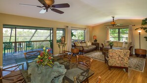 A spacious living room with a wooden floor, a sofa, chairs, a coffee table, and a ceiling fan.