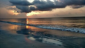 Ein Strand mit Wellen und einem Sonnenuntergang.