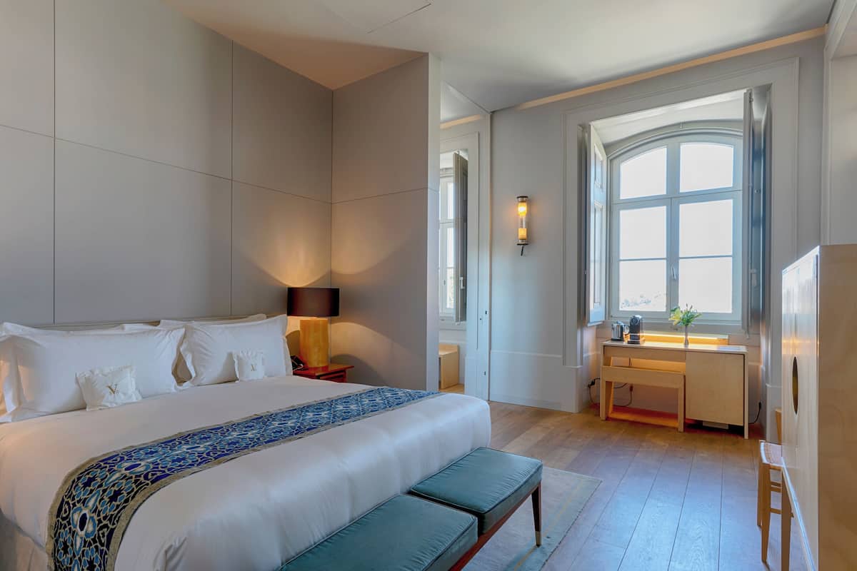 Ein modernes Hotelzimmer mit einem großen Bett, einem Schreibtisch und einem Fenster mit Blick.