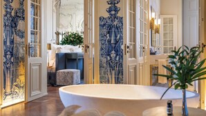 A luxurious bathroom with ornate blue and white tiles, a large bathtub, and a well-lit vanity area. - Verride Palácio Santa Catarina (Lisbon)