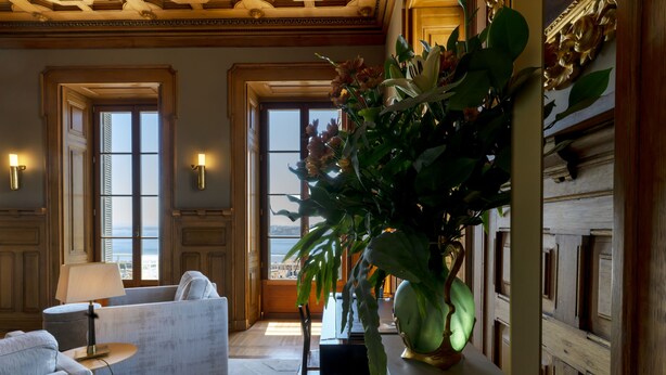 A spacious room with a large window, a sofa, a dining table, and a potted plant. - Verride Palácio Santa Catarina (Lisbon)