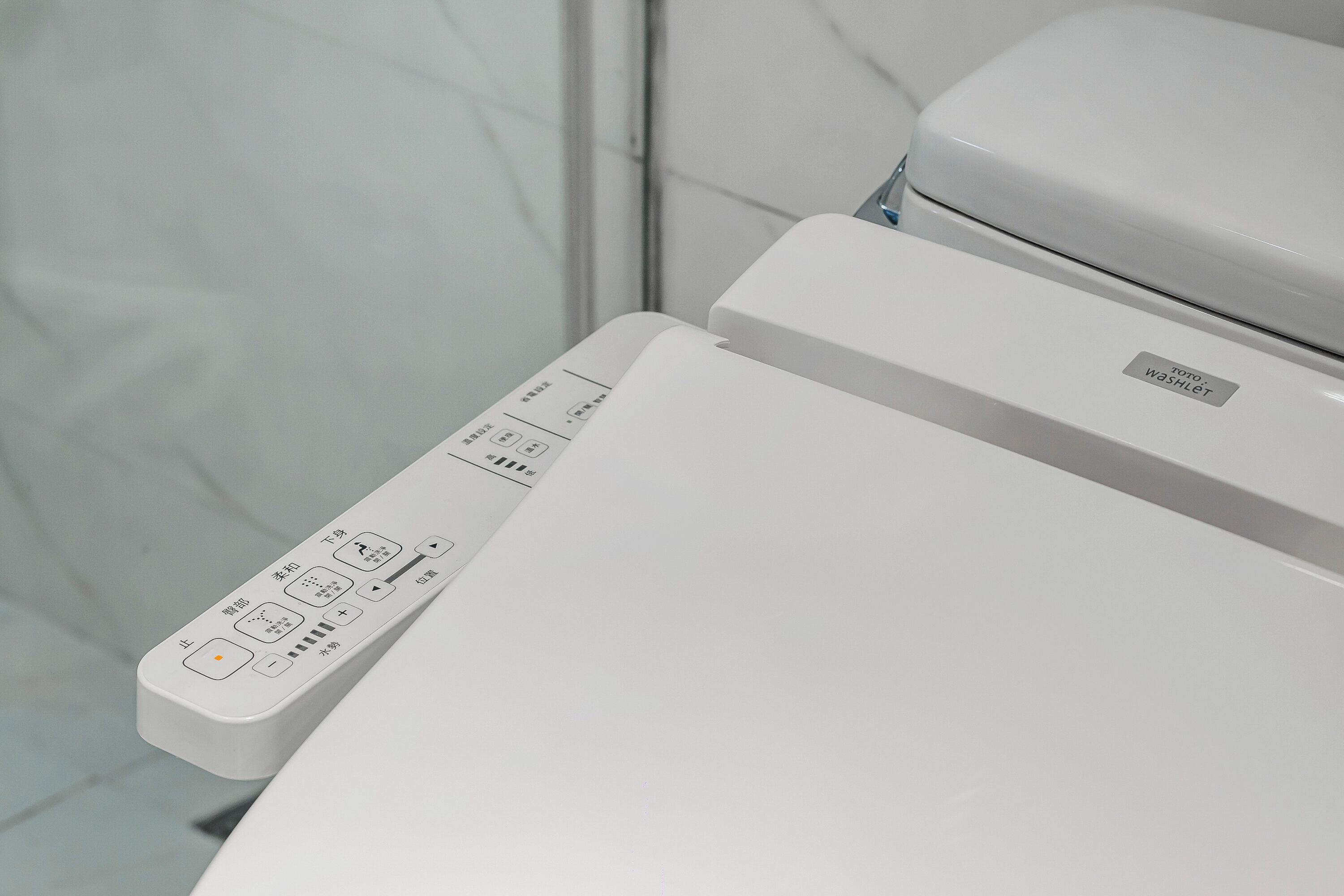 A white toilet with a control panel featuring multiple buttons and a label that reads "Poto Washlet."