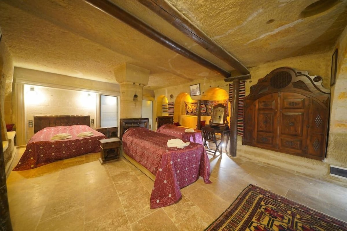 Una habitación con dos camas, un armario de madera y una alfombra estampada.
