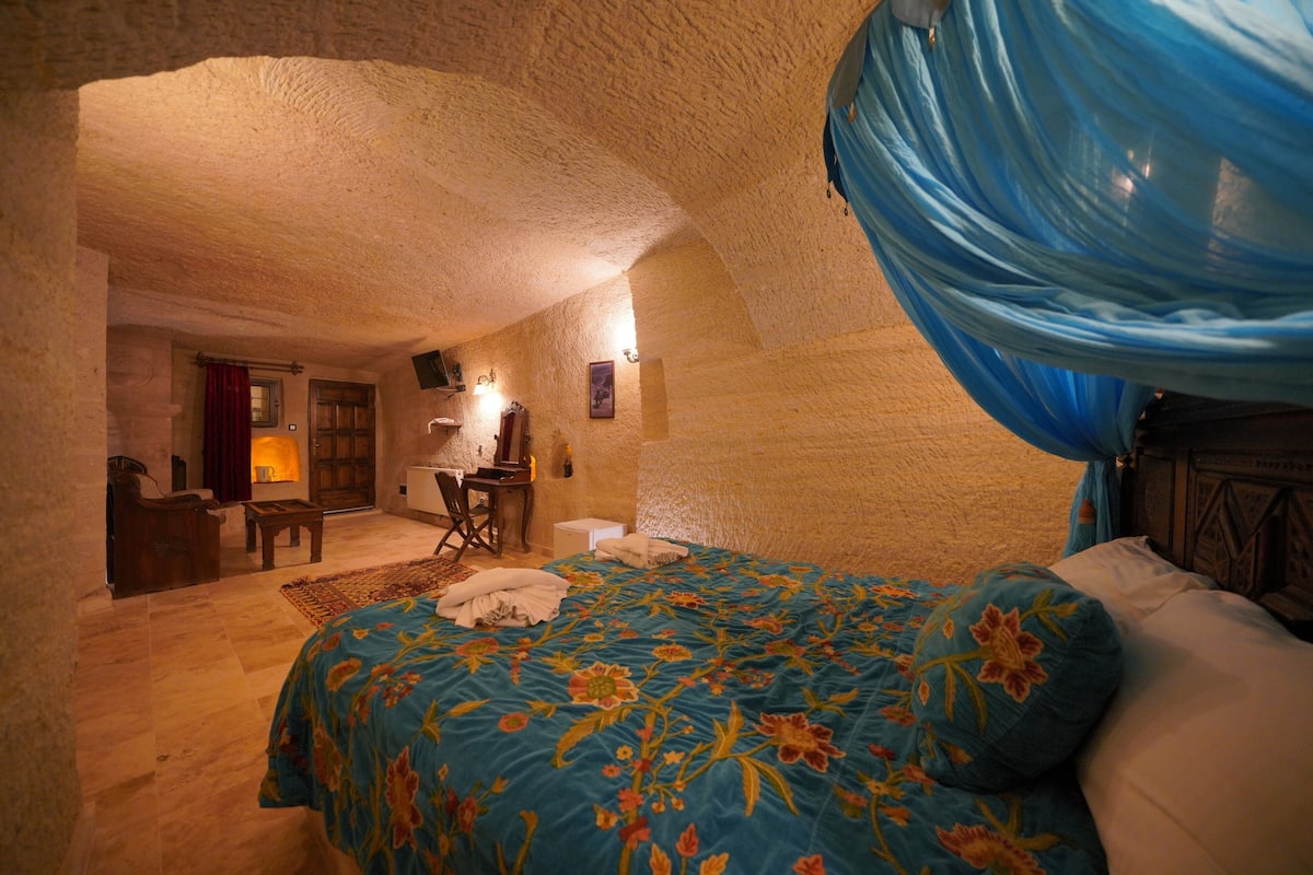 A bedroom with a floral bedspread, a wooden headboard, and a blue canopy.