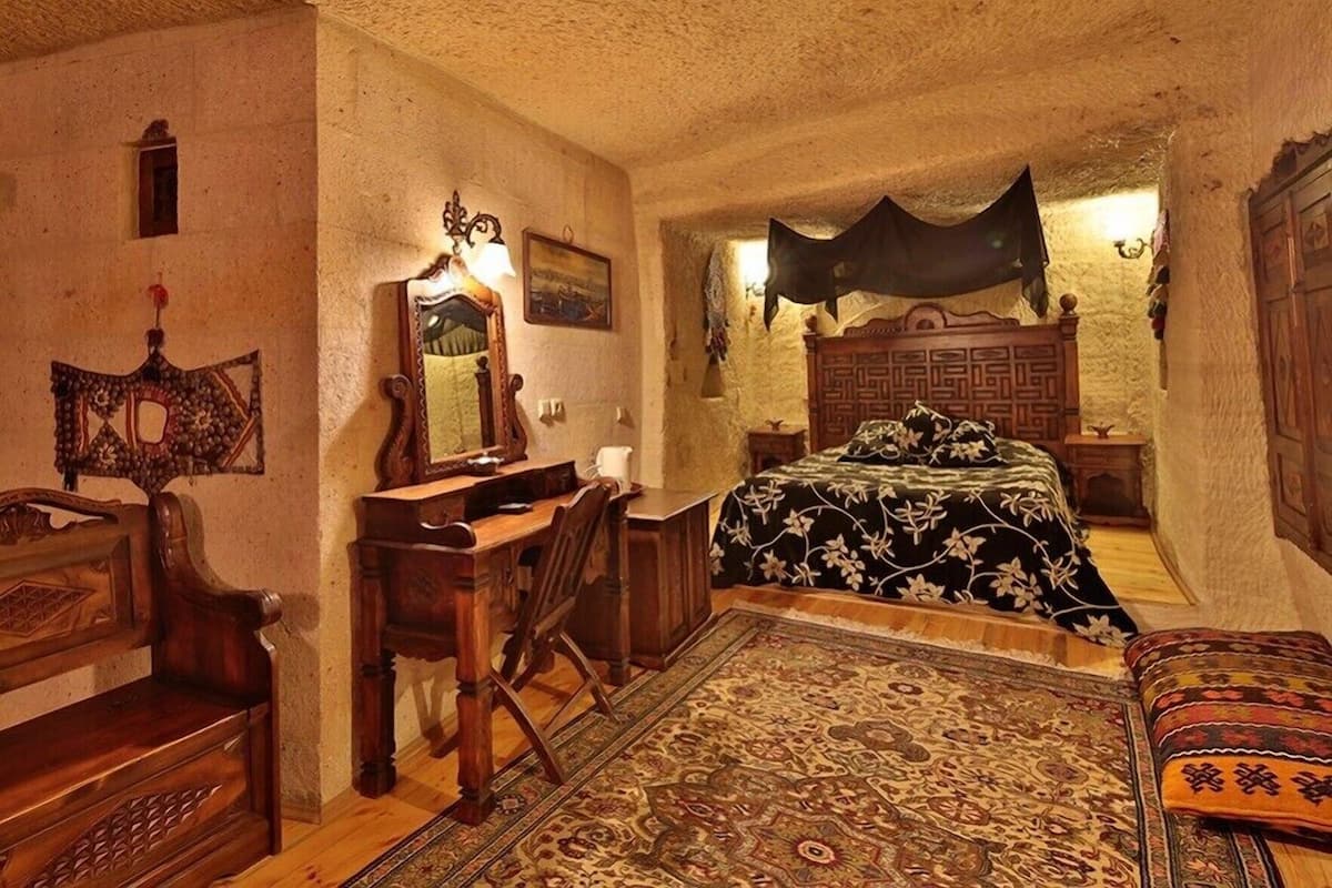 A room with a bed, desk, chair, and a large rug.
