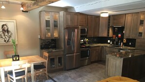 A modern kitchen with stainless steel appliances, wooden cabinets, and a dining area with a table and chairs. - Charming 2 Bdrm Condo, Peaceful Setting on Bus Line/Vail #011008 (Vail)