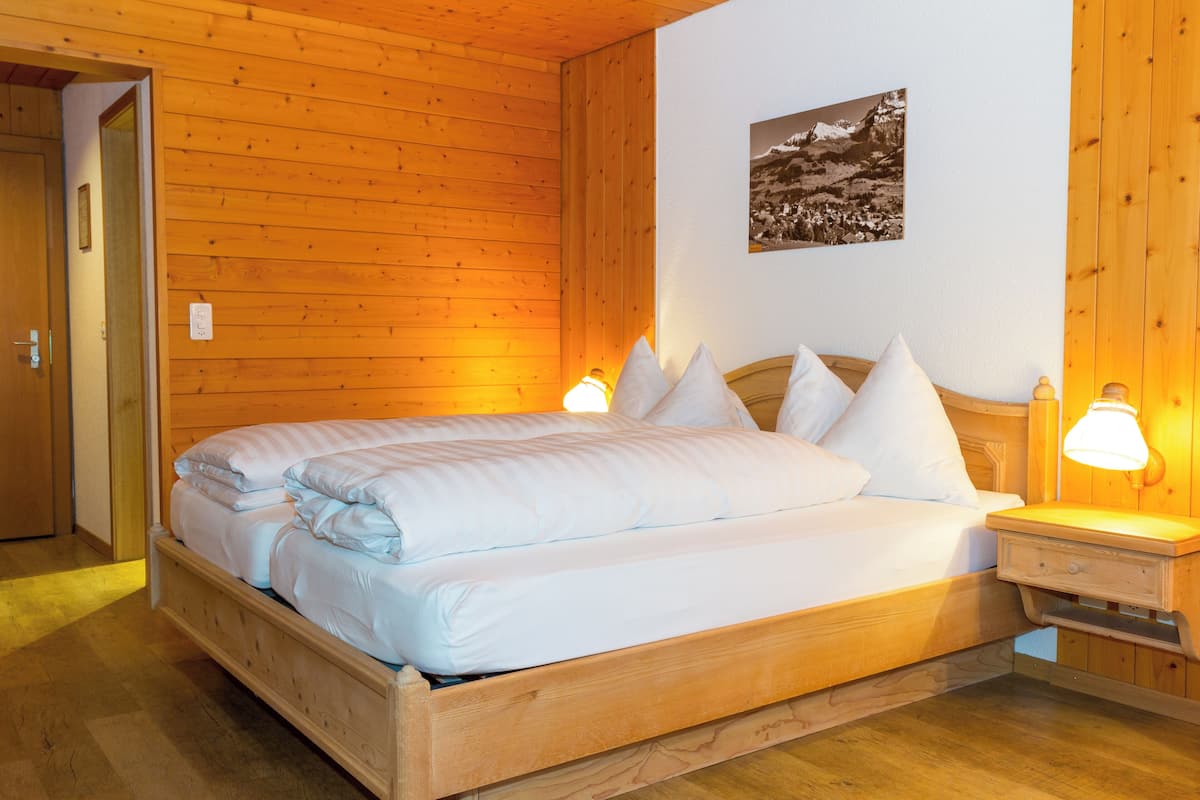 A wooden-paneled room with a bed, bedside lamps, and a framed picture on the wall.