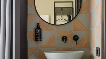 Une salle de bain avec un grand lavabo ovale, un miroir et un porte-serviettes.
