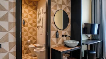 A modern bathroom with a geometric tile pattern, a round mirror, a sink, and a toilet.