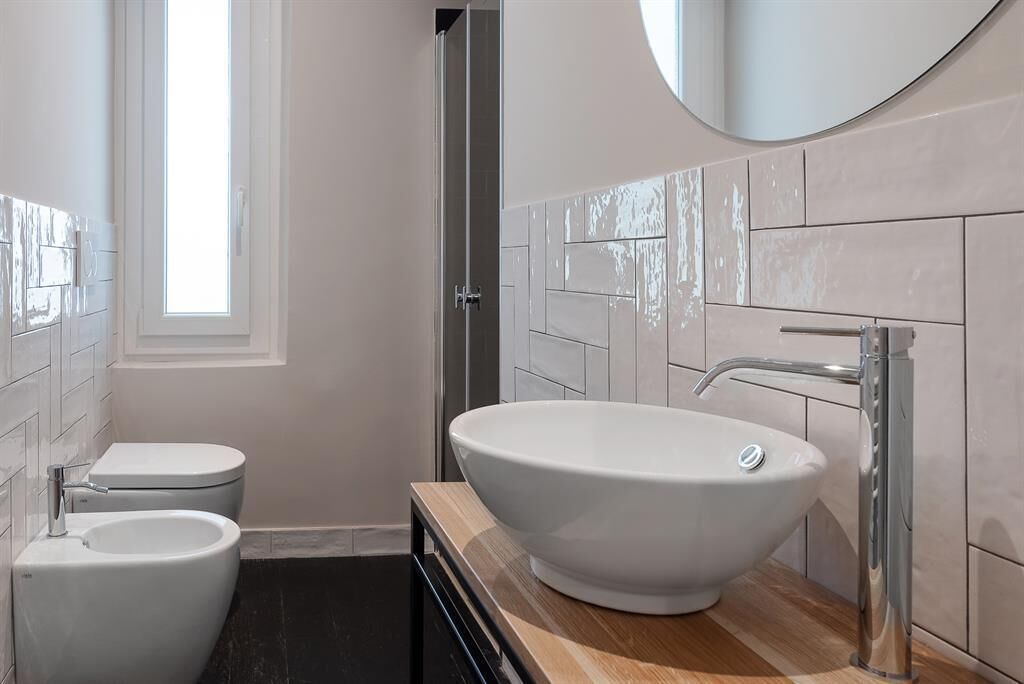 A modern bathroom with a large vessel sink, a toilet, and a shower.