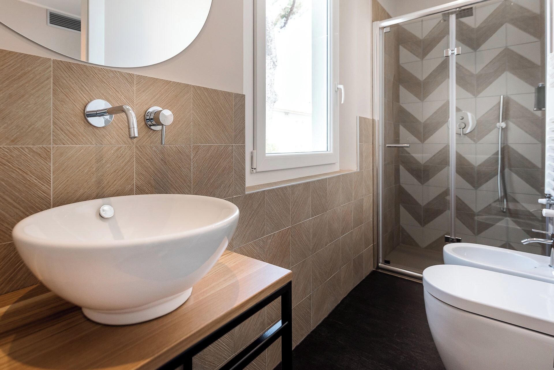 Un baño con un lavamanos grande de color blanco, un inodoro y una zona de ducha con puerta de vidrio.