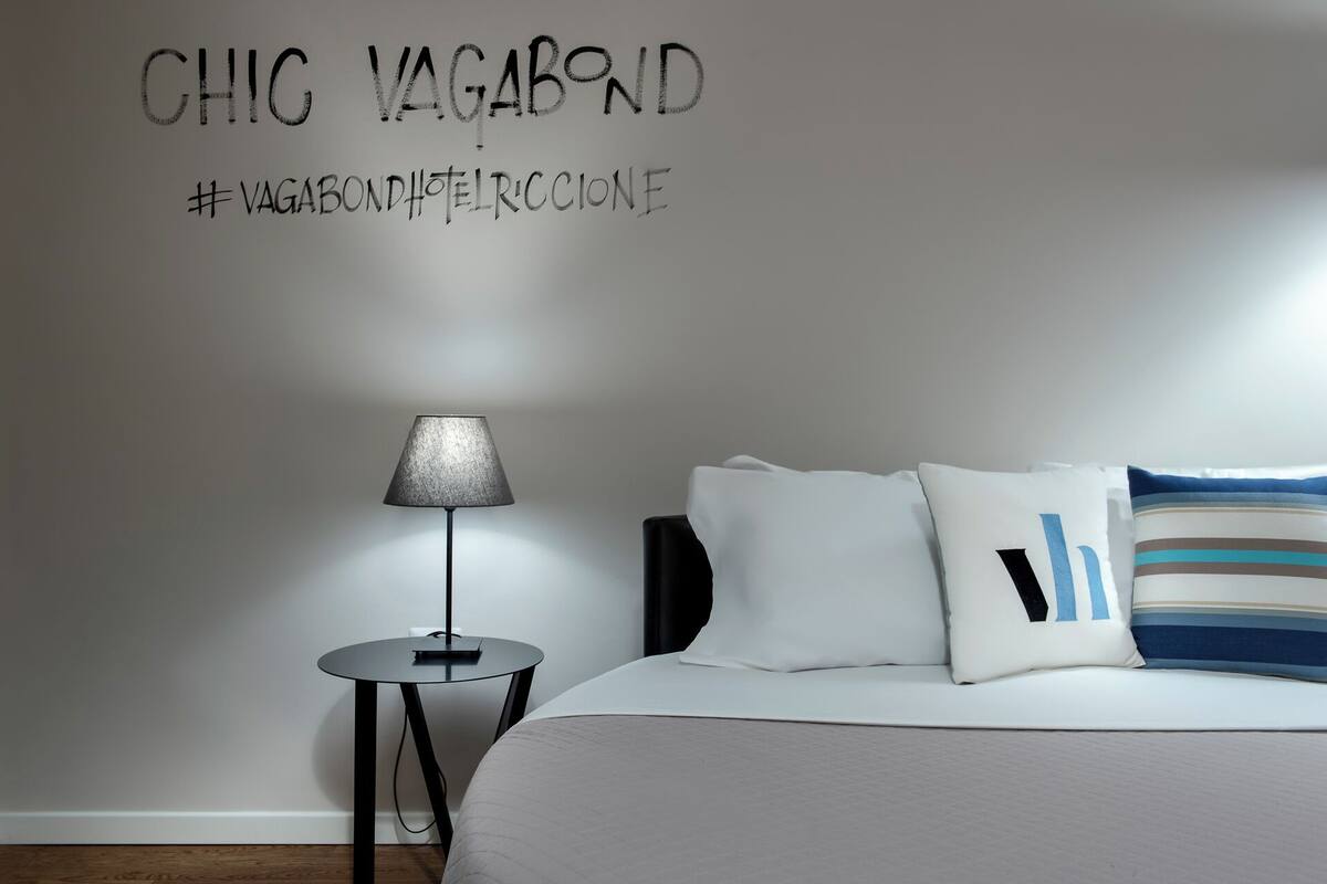 Ein Schlafzimmer mit einem Bett, einem Nachttisch, einer Lampe und einer Wand mit Text.
