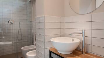 A modern bathroom with a white sink, a mirror, and a shower area.
