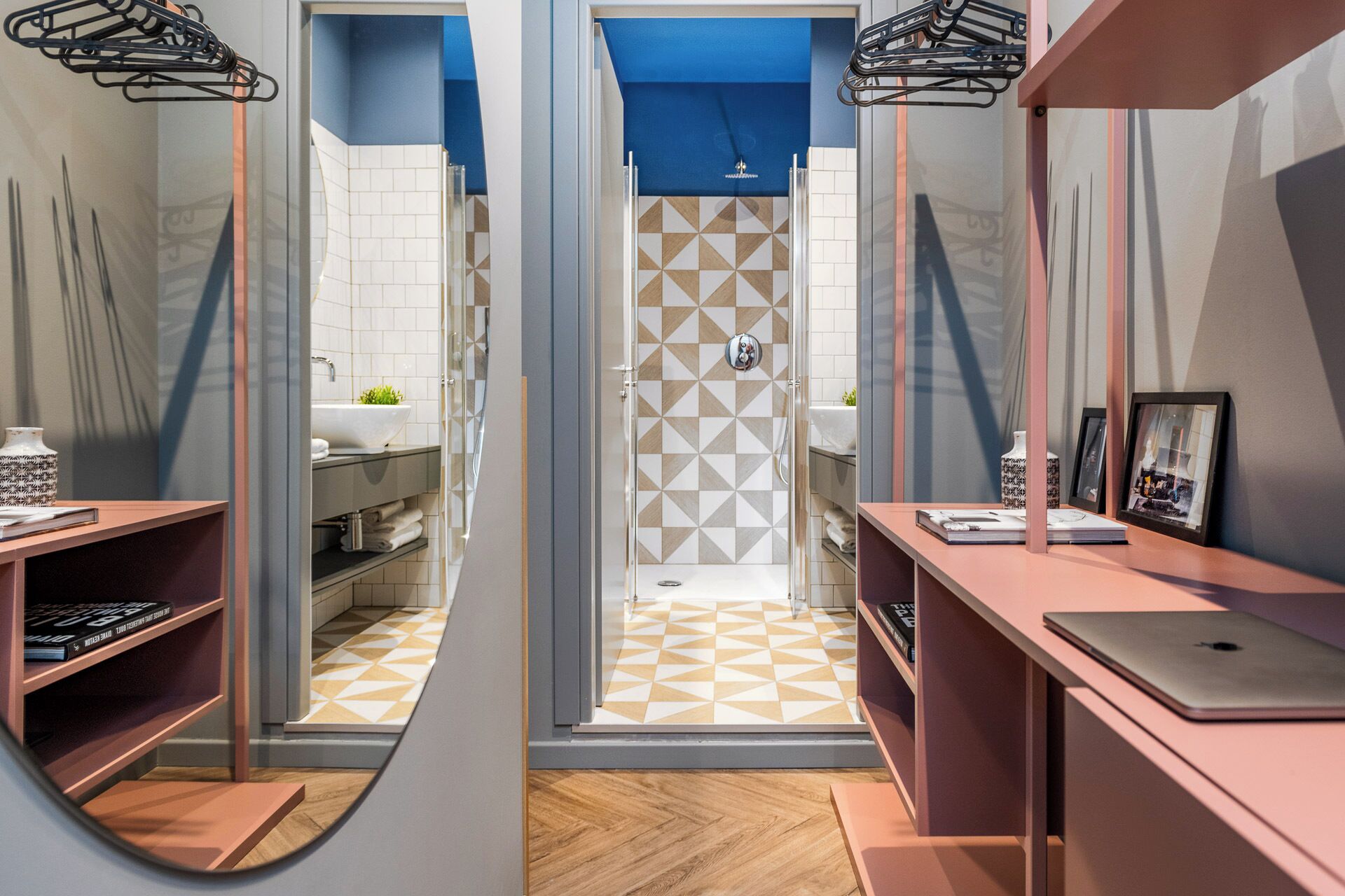 A modern bathroom with a shower, sink, and shelves with books and a vase.