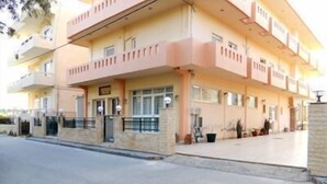 A multi-story building with a flat roof, a central entrance, and a small courtyard. - Volanakis Apartments (Malevizi)