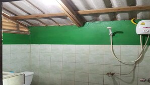 A small bathroom with a toilet, green wall, and a shower unit. - Bamboo Bungalow Thong Nai Pan Yai (Ko Pha-ngan)