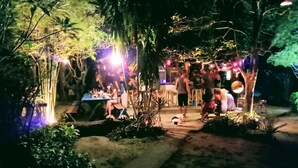 An outdoor gathering area with tables and chairs, surrounded by trees and plants. - Bamboo Bungalow Thong Nai Pan Yai (Ko Pha-ngan)