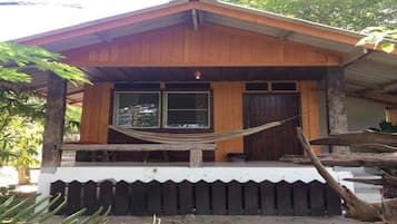 Een houten hut met een veranda, een hangmat en een houten omheining.