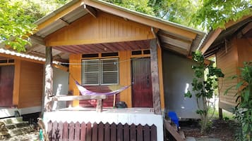 Een houten chalet met een veranda, een hangmat en een kleine trap die naar de ingang leidt.