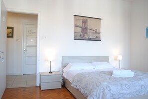 A bedroom with a bed, bedside lamps, a nightstand, a door, and a wall-mounted picture of a bridge. - Dreaming Verona Rooms (Verona)