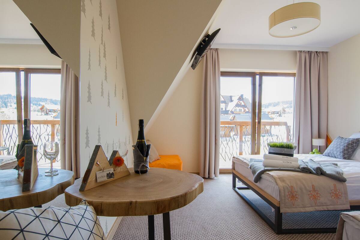 Une chambre d’hôtel avec un lit, une petite table, une fenêtre avec des rideaux et une vue sur les bâtiments environnants.