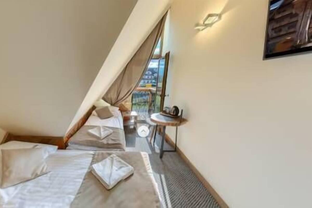 Une chambre à coucher avec un lit, des oreillers, une petite table et une fenêtre donnant sur un paysage agréable.