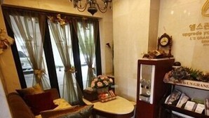 A cozy living room with a brown sofa, a small table, and a decorative cabinet with items on top. - L'S Hotel (Jeongseon)