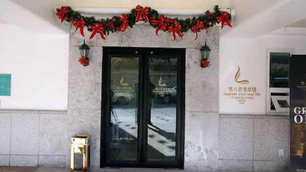 A hotel entrance with double doors, a sign with Korean text, and a garland with red bows above the doors. - L'S Hotel (Jeongseon)