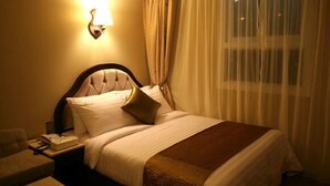A hotel room with a bed, a nightstand, a lamp, and a window with curtains. - L'S Hotel (Jeongseon)