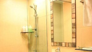 A bathroom with a glass shower enclosure, a white sink, and a mirror with a decorative tile backsplash. - L'S Hotel (Jeongseon)