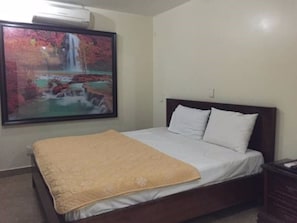 A bedroom with a bed, a painting of a waterfall, and a nightstand. - Quynh Trang Hotel (Hai Phong)