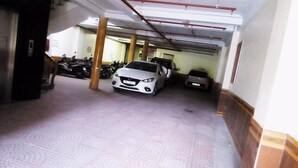A parking garage with a white car and a dark car parked in the middle. - Quynh Trang Hotel (Hai Phong)