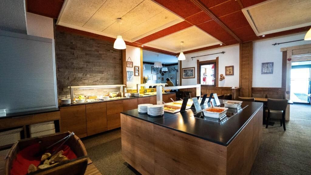 Ein Restaurant mit Holztresen, einem Buffetbereich und Sitzgelegenheiten.