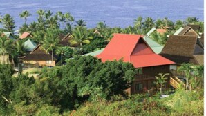 A coastal resort with multiple buildings, some with red roofs, surrounded by lush greenery and palm trees. - Ironman 2026! Easy access to Ironman & everything else!  Great Rate! Sleeps 6! (Kailua-Kona)