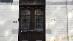 A dark wooden double door with intricate metalwork, a plaque above it, and a number '168' on the wall.