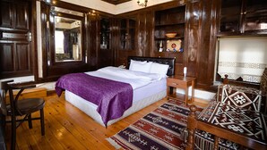 A traditional room with a large bed, wooden walls, a chandelier, and a patterned rug. - Arifbey Konagi Otel (Gaziantep)