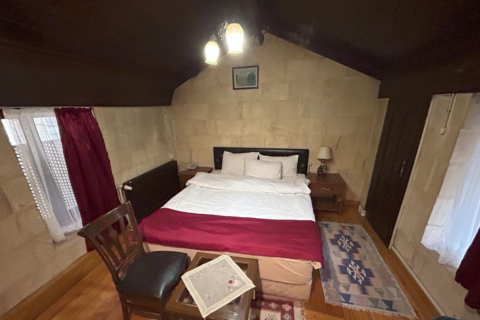 A bedroom with a bed, a chair, a nightstand, and a window with curtains.