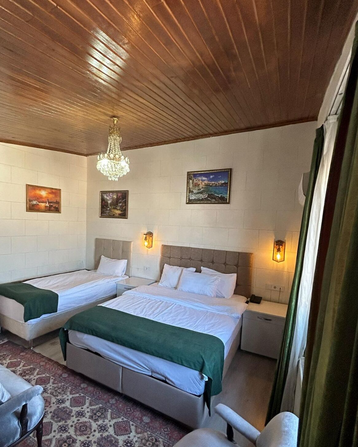 Une chambre d’hôtel avec deux lits, un lustre et des œuvres d’art accrochées aux murs.