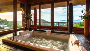 A spa area with a hot tub, large windows, and a view of the landscape. - Villa Malisa (Choeng Thale)