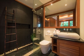 A modern bathroom with a glass-enclosed shower, a white toilet, and a wooden vanity with a large mirror.