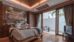 A spacious bedroom with a large bed, a television, and a sliding glass door leading to a balcony. - Villa Malisa (Choeng Thale)